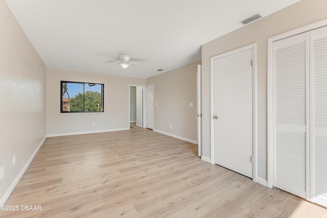 unfurnished bedroom featuring ceiling fan, two closets, and light hardwood / wood-style floors