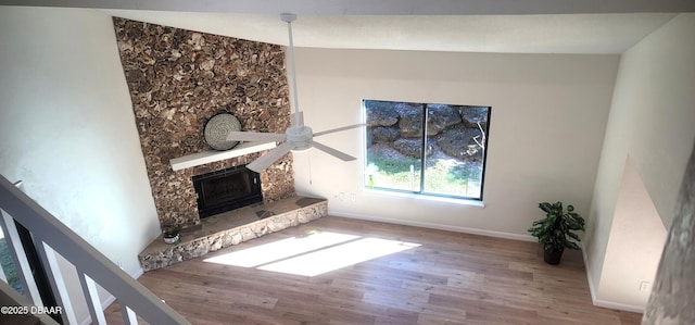 unfurnished living room with a ceiling fan, a fireplace, baseboards, and wood finished floors