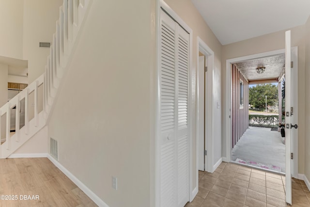 corridor featuring light tile patterned floors, visible vents, and baseboards