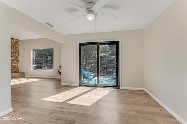 unfurnished room with a ceiling fan, light wood-type flooring, visible vents, and baseboards