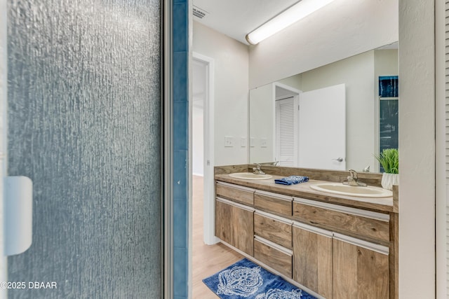 bathroom featuring double vanity, wood finished floors, a sink, and visible vents