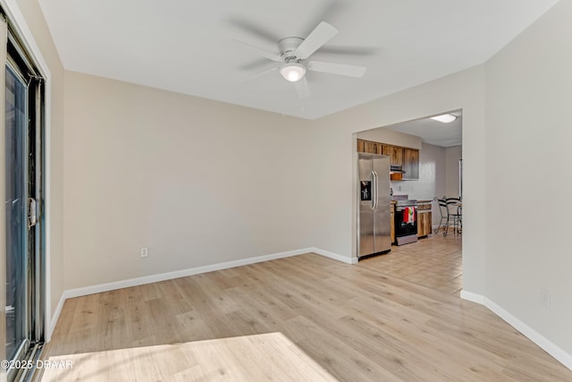 spare room with light wood-style floors, ceiling fan, and baseboards