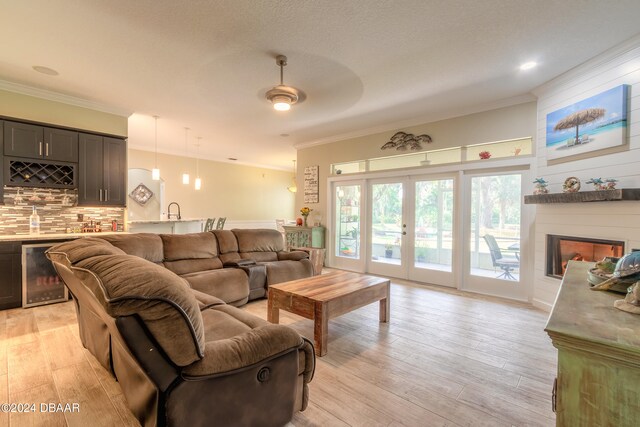 living room featuring a fireplace, light hardwood / wood-style floors, wine cooler, and ornamental molding