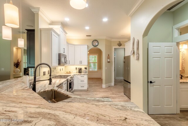 kitchen featuring white cabinetry, appliances with stainless steel finishes, decorative light fixtures, and light stone countertops