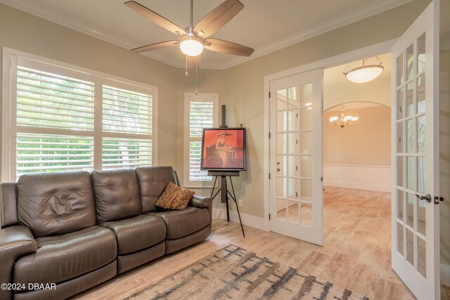 living room featuring ornamental molding, french doors, light hardwood / wood-style floors, and ceiling fan with notable chandelier