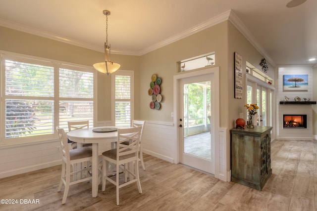 dining area with a wealth of natural light, ornamental molding, and light hardwood / wood-style flooring