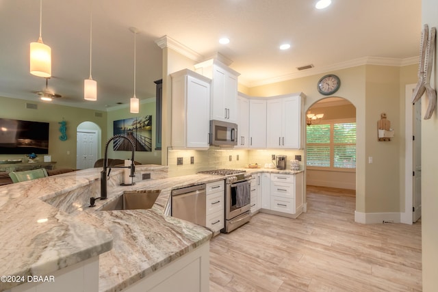 kitchen featuring light stone counters, appliances with stainless steel finishes, hanging light fixtures, sink, and white cabinets