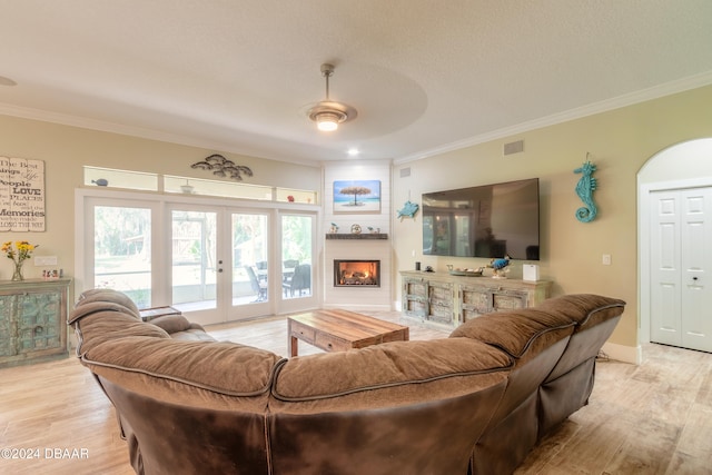 living room with ornamental molding, light wood-type flooring, french doors, and a healthy amount of sunlight