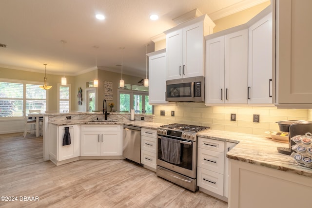 kitchen with white cabinetry, appliances with stainless steel finishes, sink, and decorative light fixtures