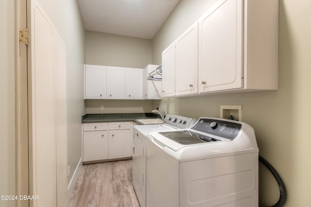 laundry area with cabinets, light hardwood / wood-style floors, sink, and washer and clothes dryer