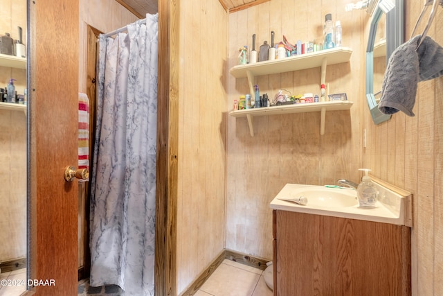 bathroom featuring tile patterned flooring, vanity, and wooden walls