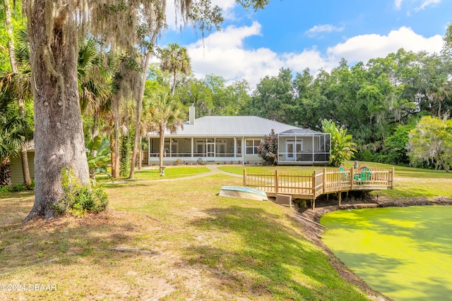 back of house with a lawn, a sunroom, and a wooden deck