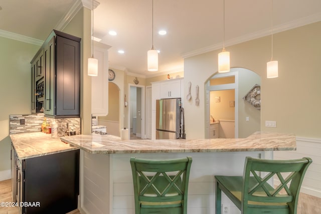 kitchen with white cabinets, kitchen peninsula, stainless steel fridge, and hanging light fixtures