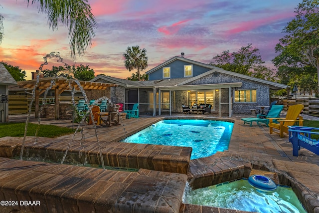 pool at dusk featuring an in ground hot tub and a patio area