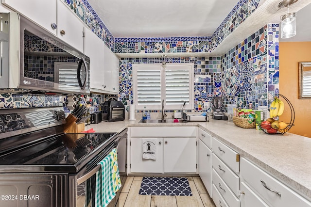 kitchen with white cabinetry, black electric range oven, a healthy amount of sunlight, and decorative light fixtures