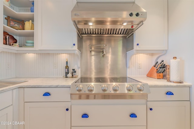 kitchen featuring white cabinets, wall chimney exhaust hood, decorative backsplash, and light stone countertops