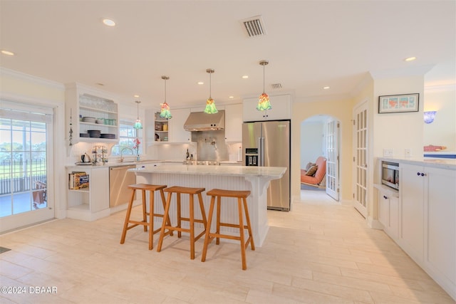 kitchen featuring stainless steel appliances, pendant lighting, a center island, white cabinetry, and a breakfast bar area