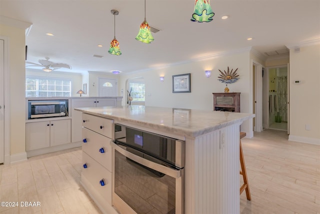 kitchen with white cabinets, appliances with stainless steel finishes, a center island, and a wealth of natural light