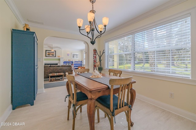 1949 Bayview Dr, New Smyrna Beach, FL 32168 - dining space with arched walkways, a fireplace, crown molding, a chandelier, and baseboards