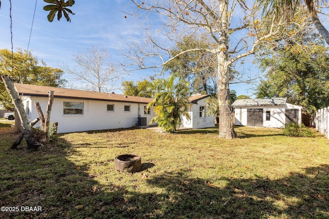 back of house featuring central AC, a yard, and a storage shed