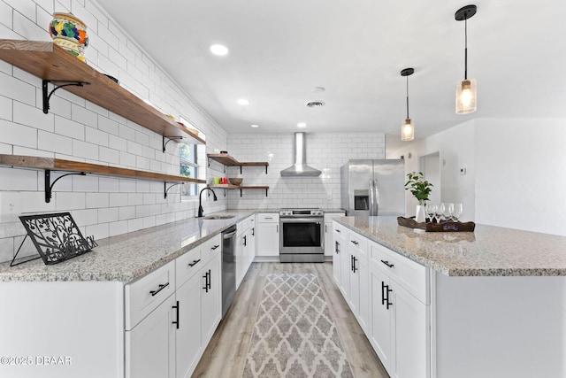 kitchen featuring backsplash, wall chimney exhaust hood, stainless steel appliances, sink, and white cabinetry