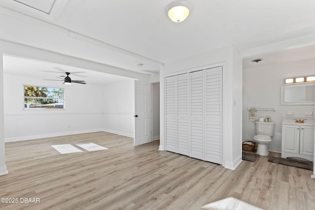 bedroom with a closet, ensuite bath, ceiling fan, and light hardwood / wood-style flooring