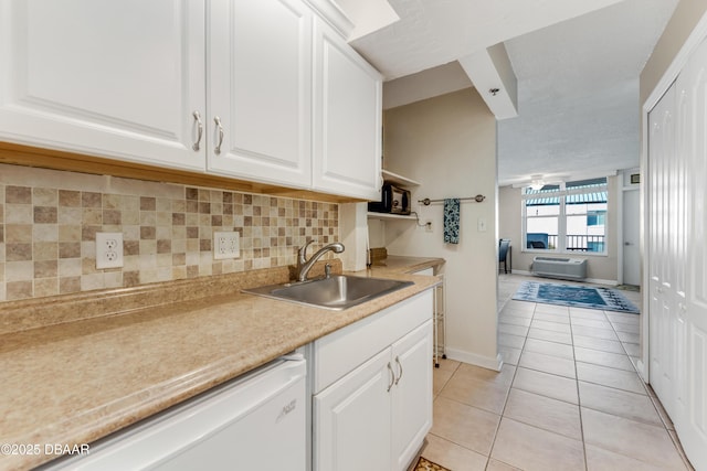 kitchen with dishwasher, white cabinetry, sink, and light tile patterned floors