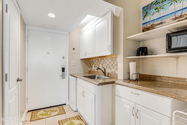 kitchen with decorative backsplash, sink, dishwasher, white cabinets, and light tile patterned flooring