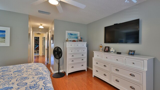 2942 Sea Oats Cir, Daytona Beach, FL 32118 - bedroom featuring a textured ceiling, a ceiling fan, visible vents, light wood finished floors, and baseboards