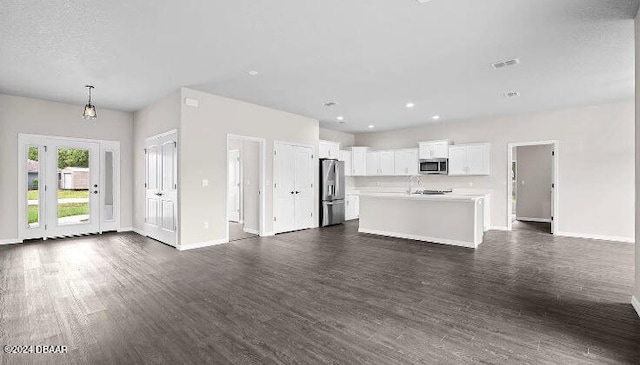 unfurnished living room with dark wood-type flooring and a textured ceiling