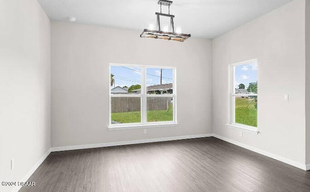 unfurnished dining area with dark wood-type flooring and a notable chandelier