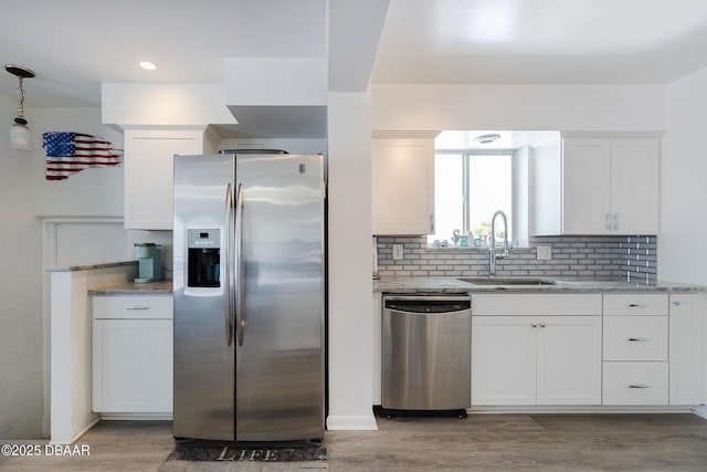 59 Arroyo Pkwy, Ormond Beach, FL 32174 - kitchen featuring stainless steel appliances, white cabinetry, light stone countertops, backsplash, and light wood-type flooring