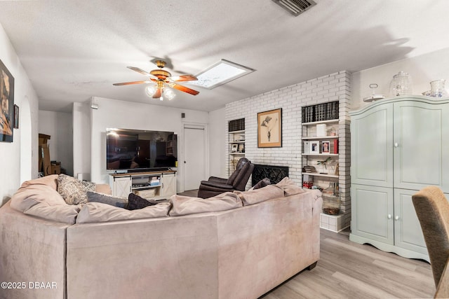 24 Tomoka Oaks Blvd, Ormond Beach, FL 32174 - living area featuring ceiling fan, a textured ceiling, light wood finished floors, a fireplace, and brick wall