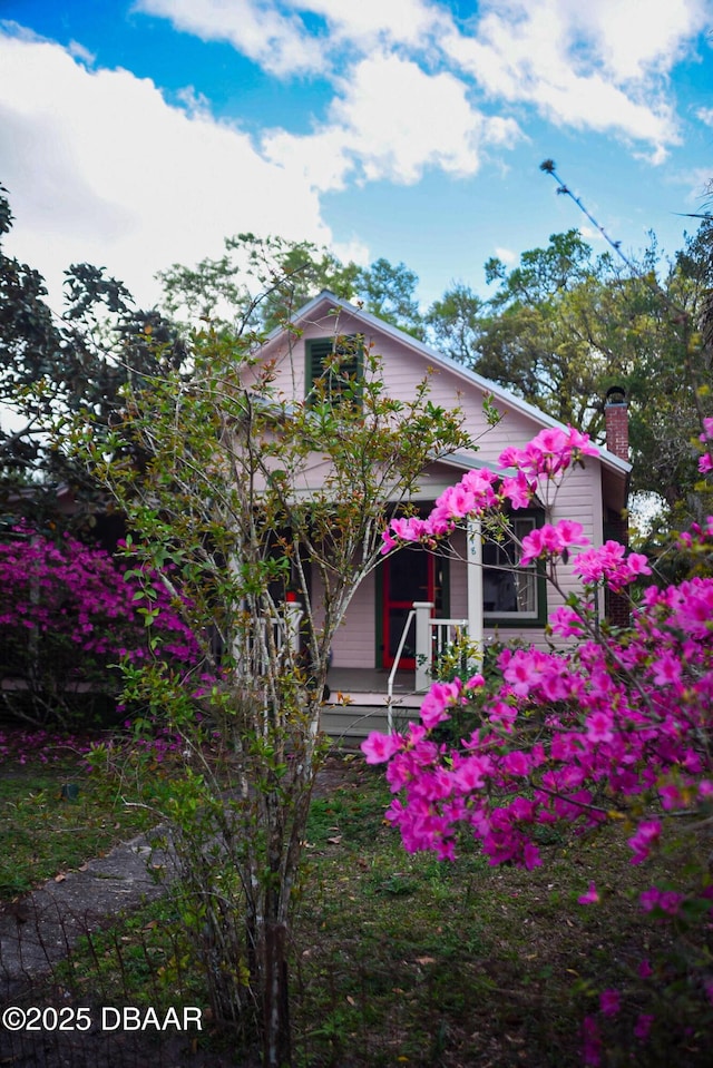 view of front of home with a chimney and covered porch