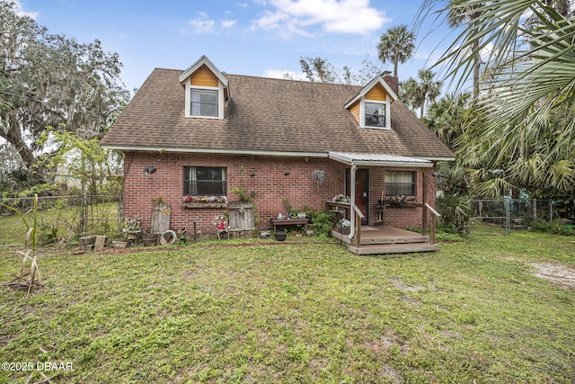 view of front facade with brick siding, fence, and a front lawn