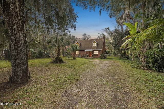 view of front facade featuring driveway, a chimney, and a front lawn