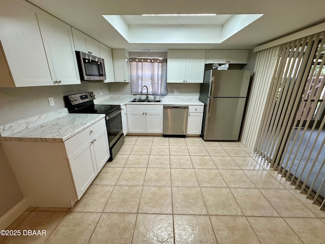 kitchen featuring white cabinetry, sink, stainless steel appliances, a tray ceiling, and light tile patterned floors