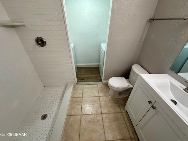 bathroom featuring tile patterned floors, vanity, toilet, and a tile shower