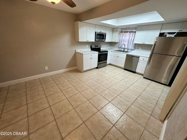 kitchen featuring appliances with stainless steel finishes, ceiling fan, sink, light tile patterned floors, and white cabinetry