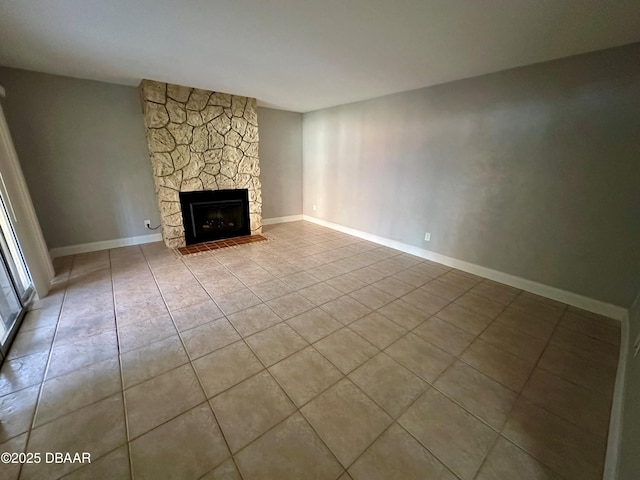 unfurnished living room featuring a stone fireplace and light tile patterned floors