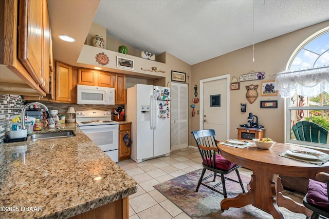 kitchen with tasteful backsplash, white appliances, a sink, and lofted ceiling