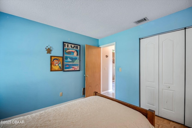bedroom featuring a closet, visible vents, and a textured ceiling