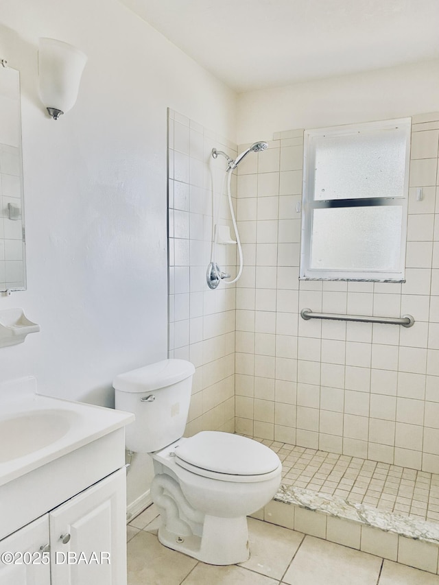 bathroom featuring tile patterned floors, vanity, toilet, and a tile shower