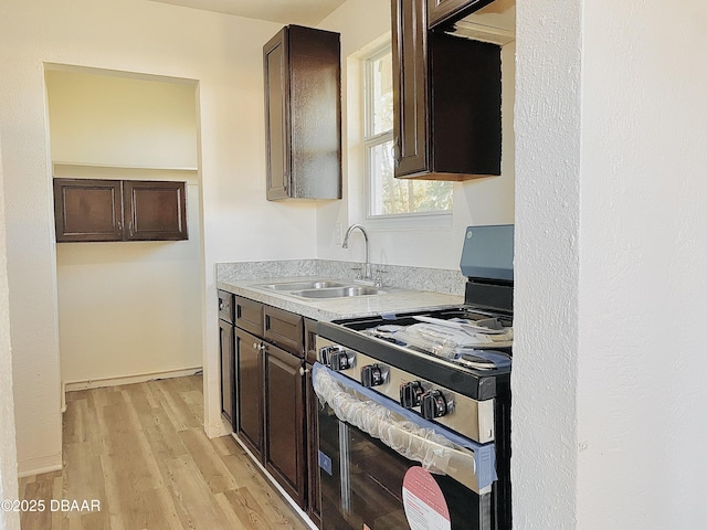 kitchen featuring light wood-type flooring, stainless steel range oven, dark brown cabinetry, and sink