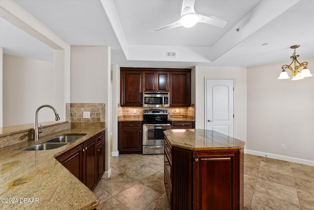 kitchen featuring backsplash, hanging light fixtures, sink, appliances with stainless steel finishes, and light stone counters