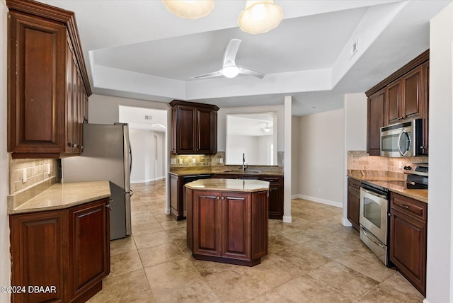 kitchen featuring ceiling fan, sink, stainless steel appliances, tasteful backsplash, and a kitchen island