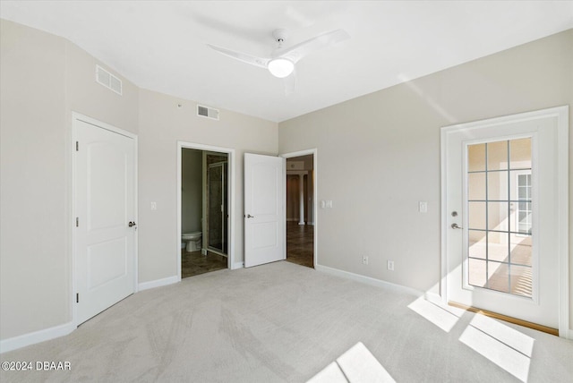 unfurnished bedroom featuring ceiling fan, light carpet, and ensuite bath