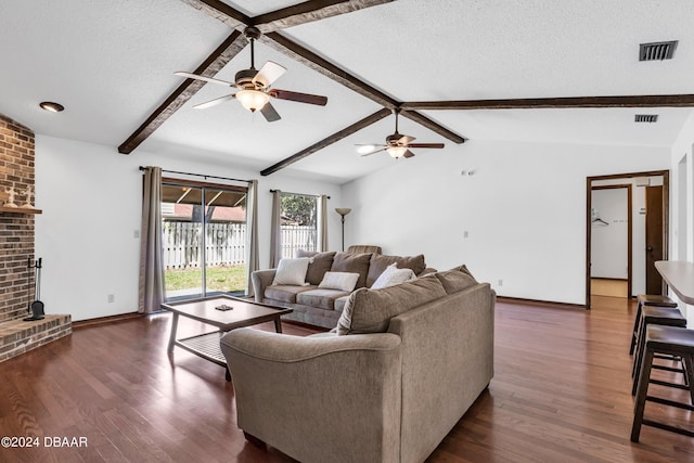 living room featuring lofted ceiling with beams, dark hardwood / wood-style flooring, ceiling fan, a brick fireplace, and a textured ceiling