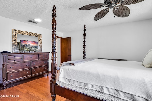 bedroom featuring dark hardwood / wood-style flooring, a textured ceiling, and ceiling fan