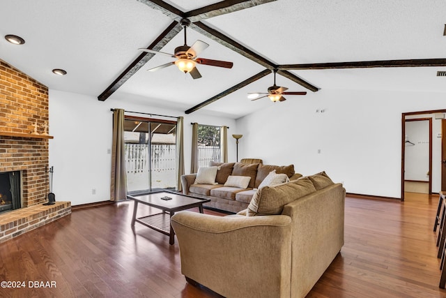 living room with lofted ceiling with beams, a brick fireplace, a textured ceiling, dark hardwood / wood-style flooring, and ceiling fan